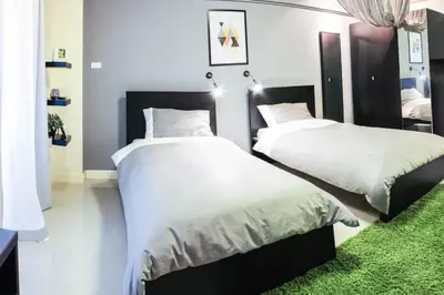 a bedroom with two beds with white sheets and a green rug at A18 in Nonthaburi