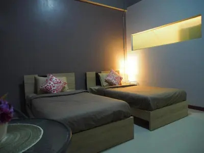 a room with two beds and a table with a lamp at Sriyanar Place in Bangkok