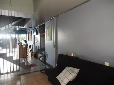 a living room with a black couch and a staircase at Sriyanar Place in Bangkok