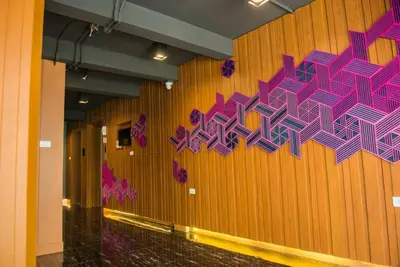 a wall with purple and purple art on it at GN Luxury Hostel in Bangkok