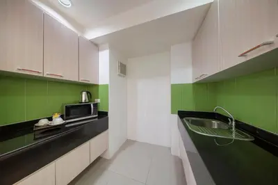 a kitchen with green and white cabinets and a sink at At 115 Hotel By Rompo in Bangkok
