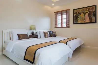 two beds in a bedroom with white walls at The Lek Aree in Bangkok