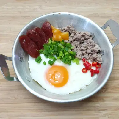 a bowl of breakfast food with eggs sausage and peppers at The Lek Aree in Bangkok