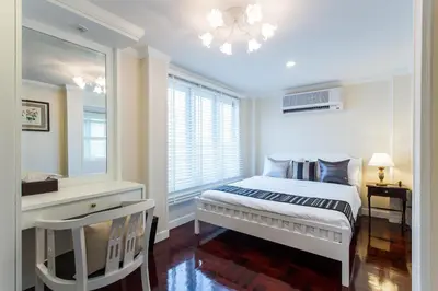 a white bedroom with a bed and a window at The Lek Aree in Bangkok