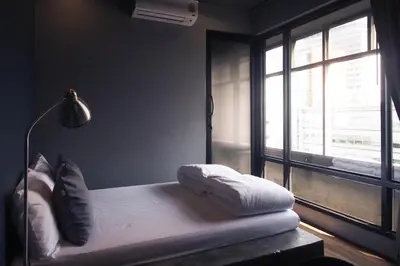 a bedroom with a bed with pillows and a window at Silom Space Hostel in Bangkok