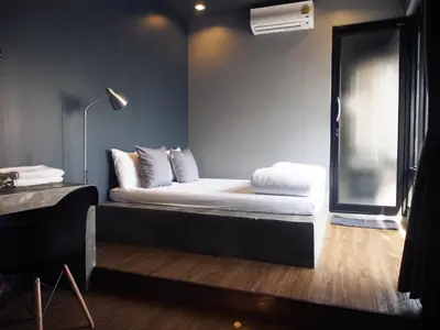 a room with a bed and a lamp and a window at Silom Space Hostel in Bangkok