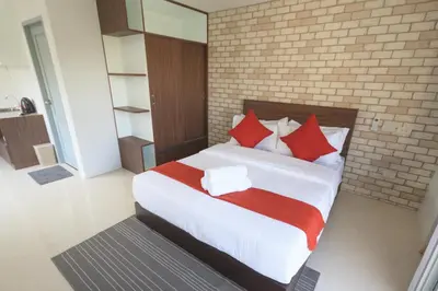 a bedroom with a large white bed with red pillows at Q Space Residence in Bangkok