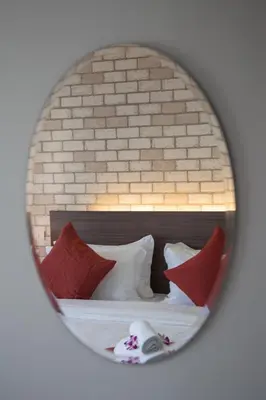 a mirror reflecting a bed with red and white pillows at Q Space Residence in Bangkok