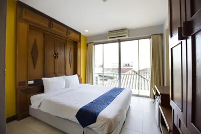 a bedroom with a large bed and a large window at Lamphu Tree House Boutique Hotel in Bangkok