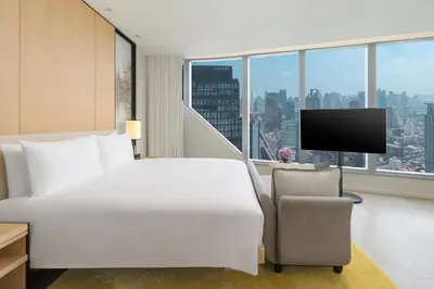 a hotel room with a bed and a chair and a television at Park Hyatt Bangkok in Bangkok