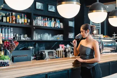 a woman standing at a bar drinking a glass of wine at The Salil Hotel Sukhumvit 57 - Thonglor in Bangkok