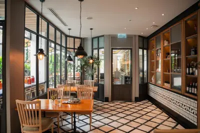 a dining room with a table and chairs and windows at The Salil Hotel Sukhumvit 57 - Thonglor in Bangkok