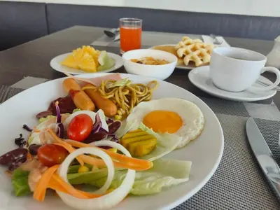 a plate of food with an egg and vegetables on a table at Anajak Bangkok Hotel - SHA Plus in Bangkok