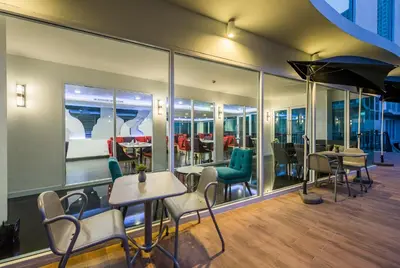 a restaurant with tables and chairs and windows at Anajak Bangkok Hotel - SHA Plus in Bangkok