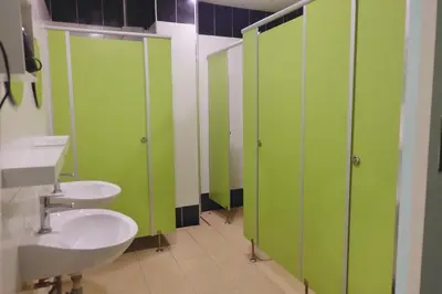 a bathroom with two sinks and green stalls at Mahannop Hostel in Bangkok
