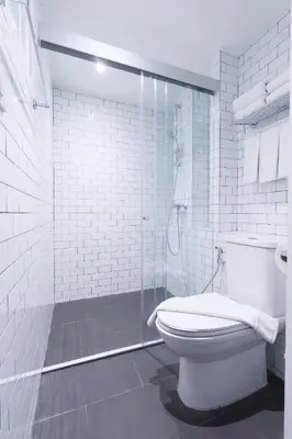 a white bathroom with a toilet and a shower at Klub Hotel Bangkok in Bangkok