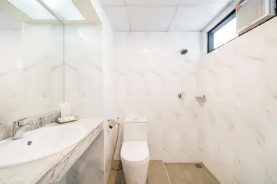 a white bathroom with a sink and a toilet at Niran Grand Hotel in Bangkok