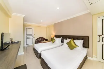 a hotel room with two beds and a television at Niran Grand Hotel in Bangkok