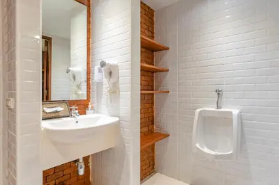 a white bathroom with a sink and a urinal at Siam Plug In Hostel in Bangkok