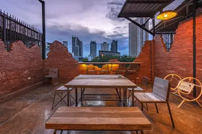 a patio with tables and chairs and a city skyline at Siam Plug In Hostel in Bangkok