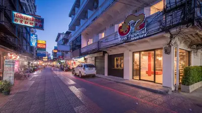 a city street with a white car parked in front of buildings at Norn Yaowarat Hotel in Bangkok