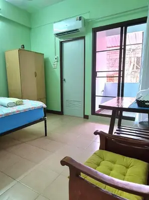 a room with a bed and a table and a window at Roong-Arun Apartment in Bangkok