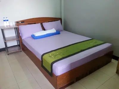 a bedroom with a bed with a wooden headboard at Roong-Arun Apartment in Bangkok