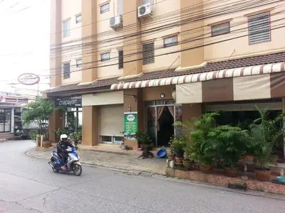 a man on a motorcycle parked in front of a building at Roong-Arun Apartment in Bangkok