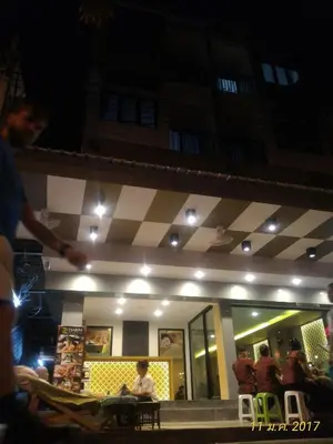 a woman sitting in front of a restaurant at night at Darin Hostel in Bangkok