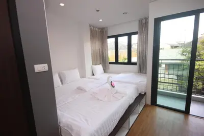 a bedroom with two beds with white sheets and a window at Darin Hostel in Bangkok