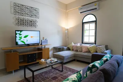 a living room with a couch and a tv at Neveu Premier Residence : Ratchada in Bangkok