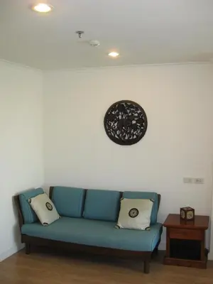 a blue couch in a living room with a clock on the wall at Bangkok view in Pinklao in Bangkok