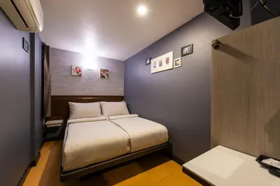 a small room with a bed and a table at BB House Phra Athit บีบี เฮ้าส์ พระอาทิตย์ in Bangkok