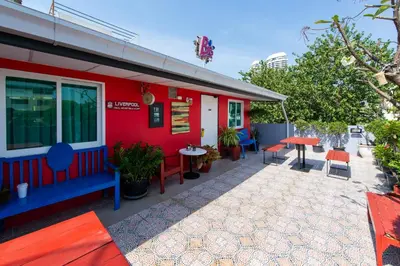 a red building with a patio with tables and chairs at BB House Phra Athit บีบี เฮ้าส์ พระอาทิตย์ in Bangkok