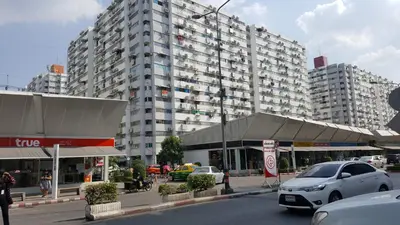 a parking lot with cars parked in front of a large building at Popular Condo C8 in Nonthaburi