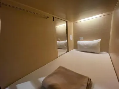 a small room with a bed and a mirror at ORA Hostel Bangkok in Bangkok