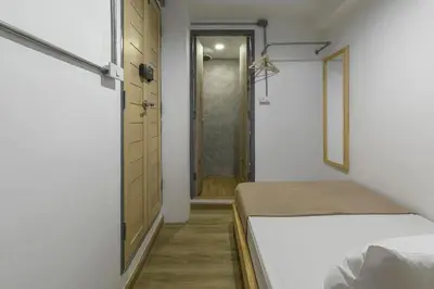 a bedroom with a bed and a door to a closet at ORA Hostel Bangkok in Bangkok