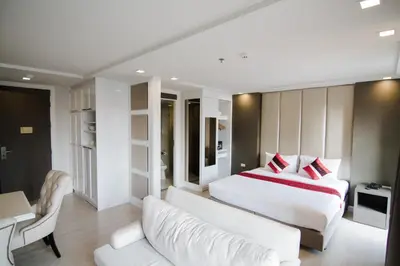 a bedroom with a white bed and a white couch at Hope Land Hotel Sukhumvit 8 in Bangkok
