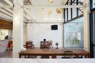 a dining room with a table and chairs and a wall at Boon Street Hostel in Bangkok