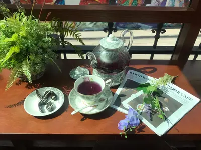 a table with a cup of tea and a plate of flowers at Siam Champs Elyseesi Unique Hotel in Bangkok