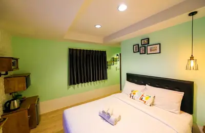 a bedroom with a bed with white sheets and green walls at Adagio Bangkok in Bangkok