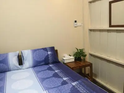 a bedroom with a bed with blue pillows and a table at Donmuang At Last in Bangkok