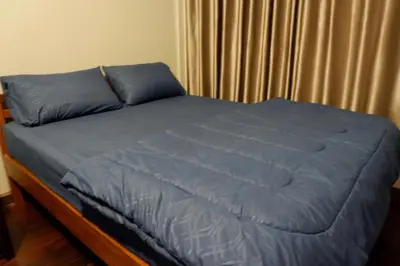 a bed with blue sheets and pillows in a bedroom at Donmuang At Last in Bangkok