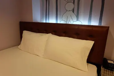 a bed with a brown headboard and a white pillow at Rabbit Room in Bangkok