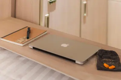 a laptop computer sitting on a wooden table at Kinnon Deluxe Hostel Coworking Cafe in Bangkok