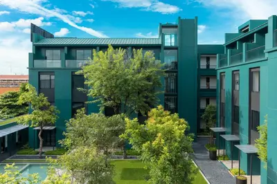 an exterior view of a green building with trees at Theatre Residence in Bangkok