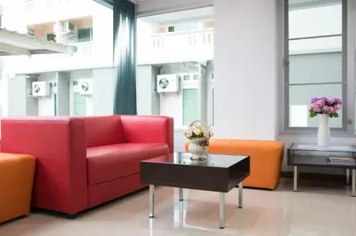 a living room with a red couch and orange chairs at Jr Mansion On Nut Soi 25 in Bangkok