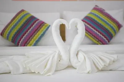 two towel swans sitting on a bed with pillows at Jr Mansion On Nut Soi 25 in Bangkok