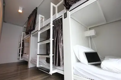 a bedroom with white bunk beds and a laptop at Diff Hostel in Bangkok
