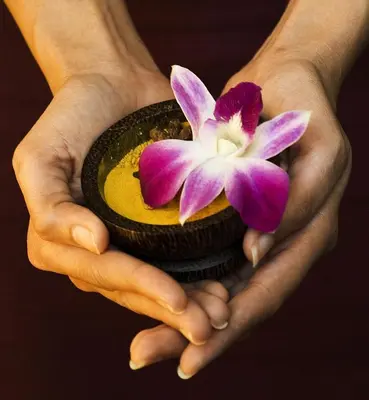 a pair of hands holding a bowl with a flower in it at Zenith Sukhumvit Hotel, Bangkok in Bangkok